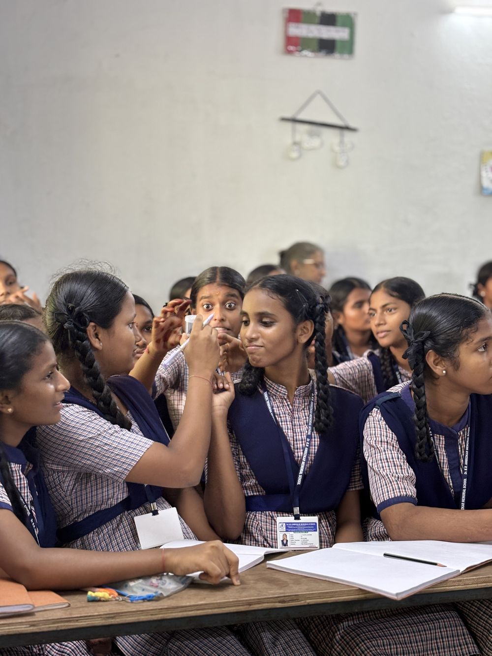 Schoolgirls in uniform crowd around a specimen jar, one peering at it wide-eyed